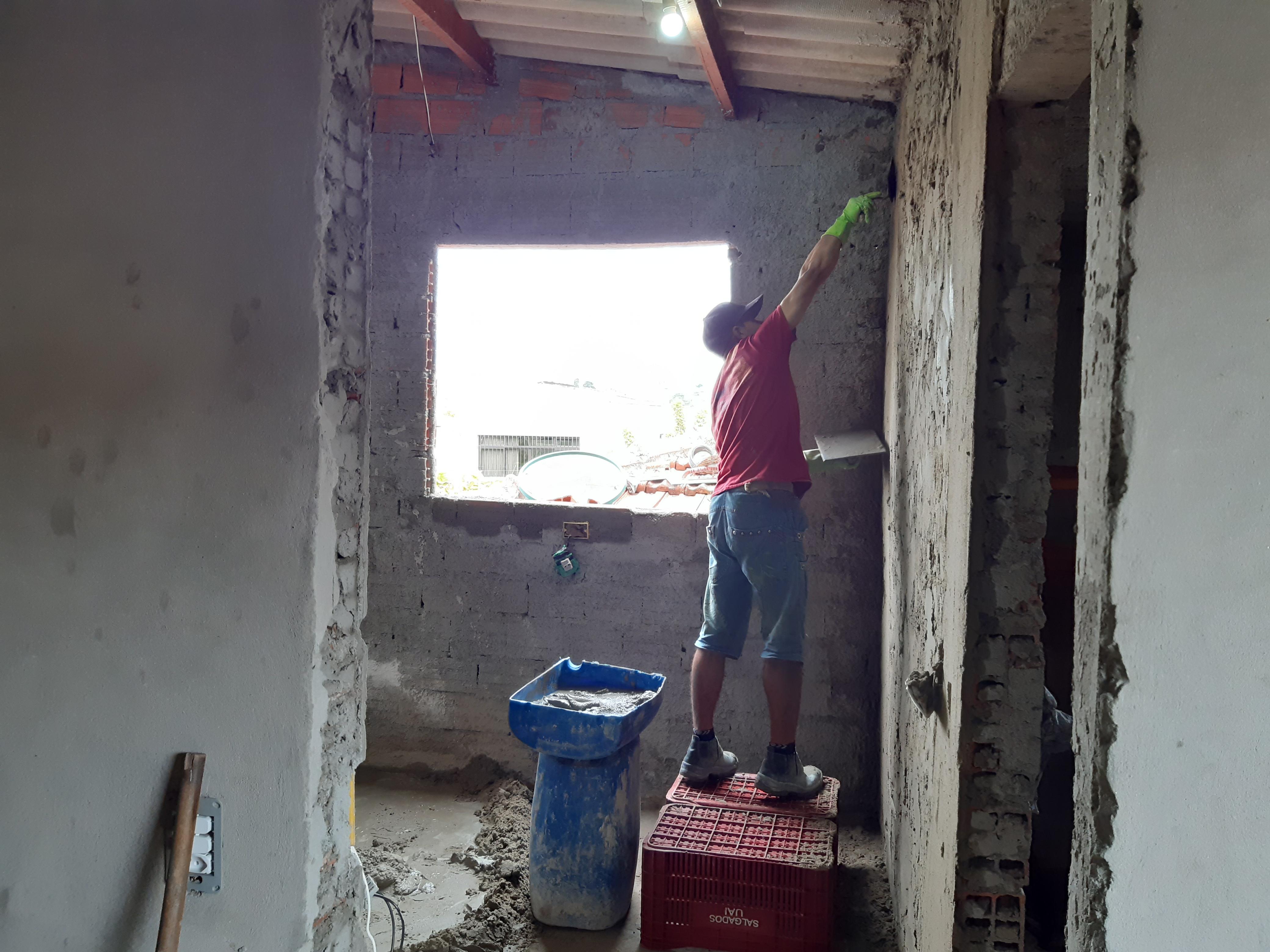 trabalhador em construção, pintando parede em uma sala em obras