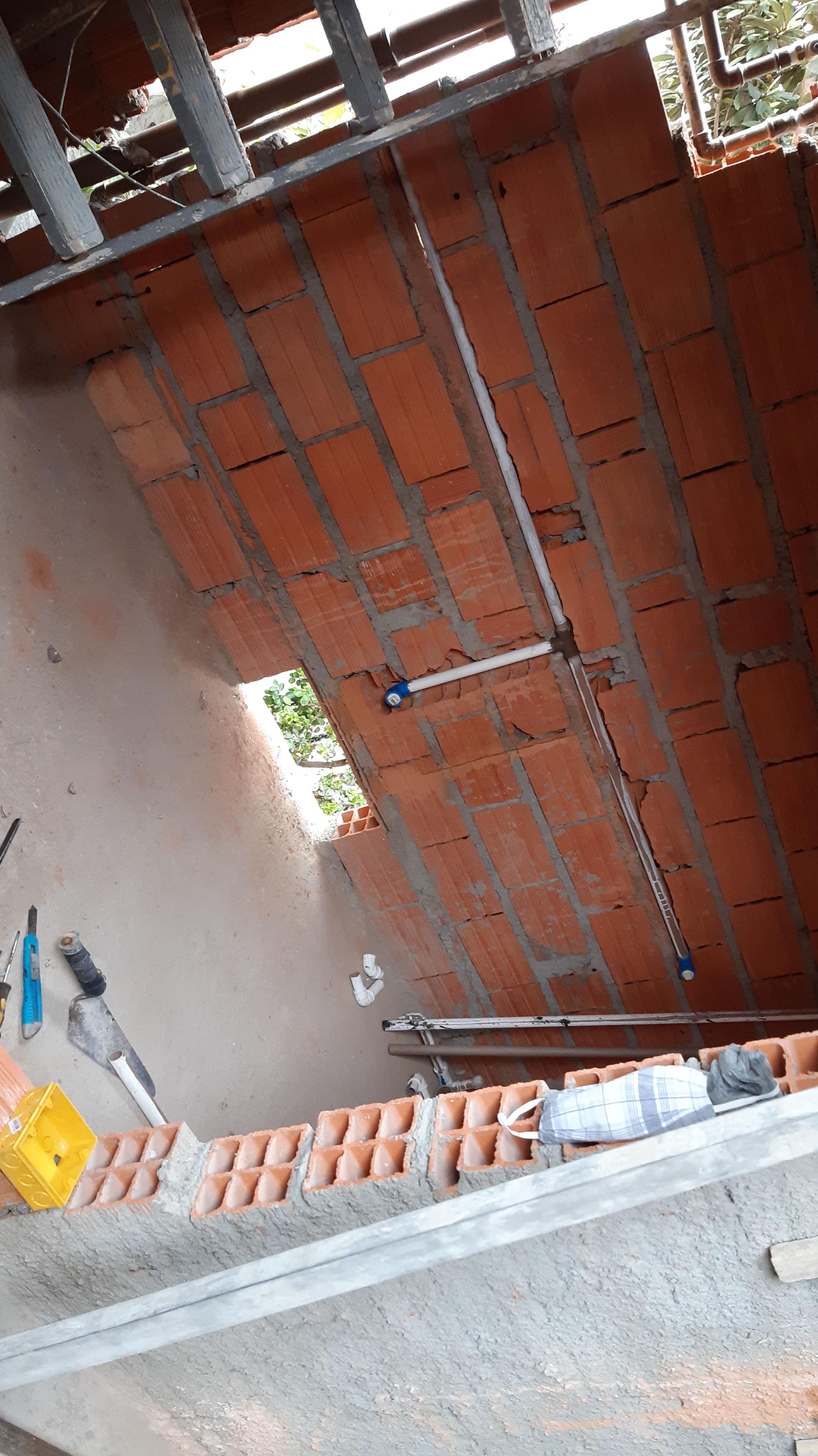 parede de tijolos vermelhos em construção com ferramentas e materiais de obra ao redor
