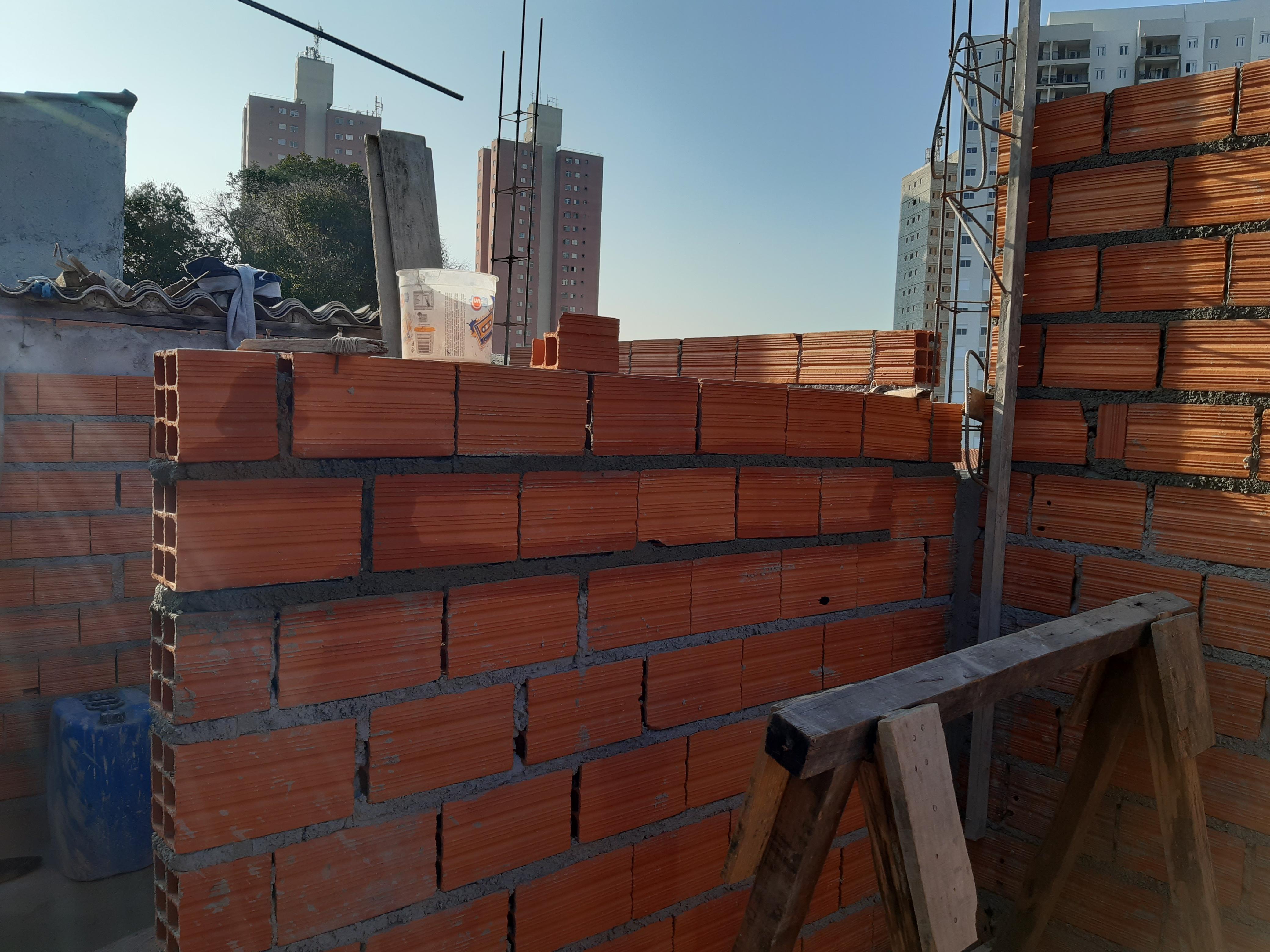 fotos de um trabalho de construção com paredes de tijolos vermelhos, ferramentas e edifícios altos no fundo