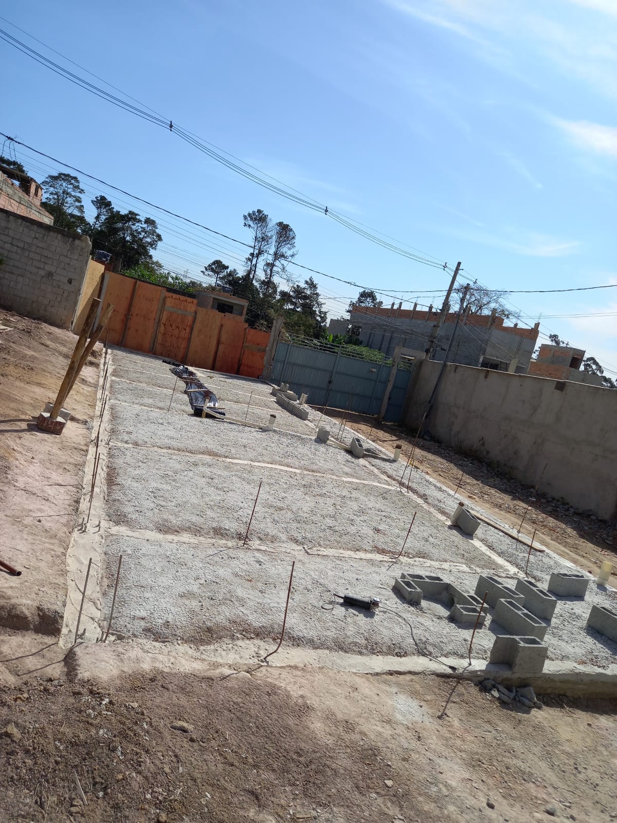Laje de base da fundação com brita, blocos de concreto e ferragens no terreno