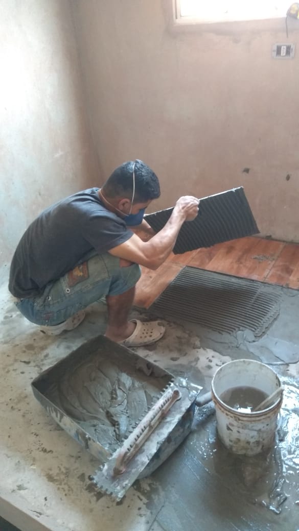 Pedreiro cortando peça de revestimento com a masseira ao lado